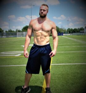 Picture of the owner and transformation coach of bestpersonaldevelopmentcourses.com Sean, standing in the middle of the field looking like a muscular athlete